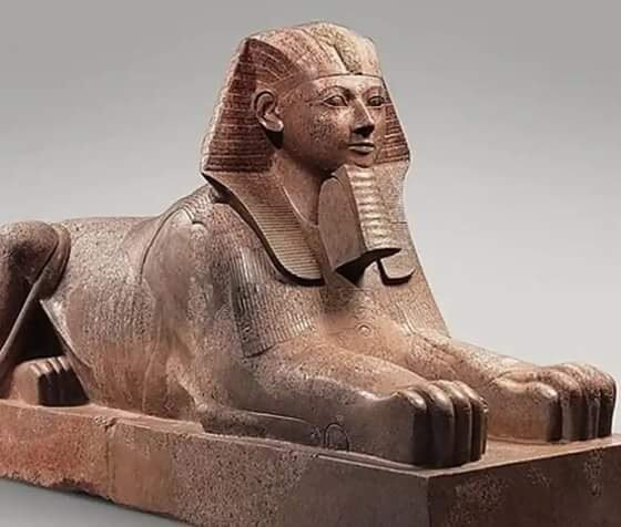 Colossal granite statue of Hatshepsut portrayed as a muscular male king, wearing a false beard and kilt, emphasizing her royal transformation.