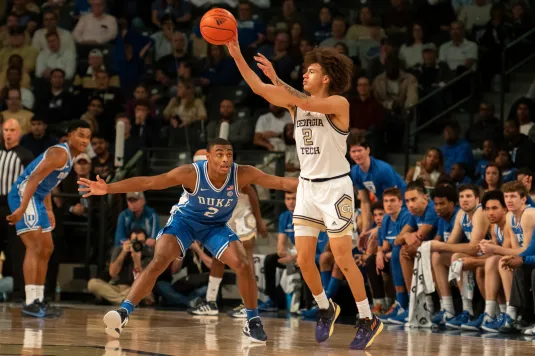 Georgia Tech player dunks over Duke defender in intense ACC basketball rivalry matchup